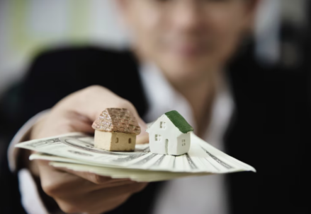 man in a classic suit hands out money with houses on it