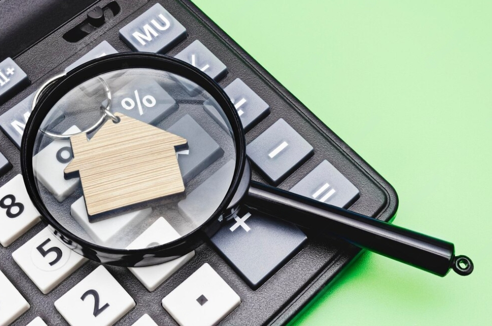 calculator, wooden house, and magnifying glass on it