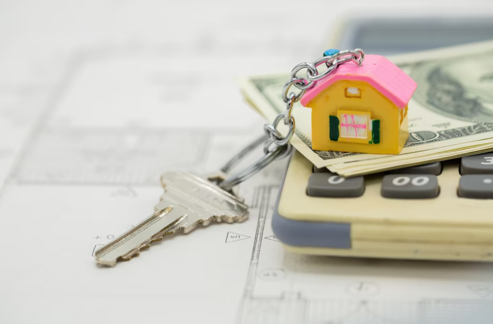 small pink house and money on calculator, keys on sheet