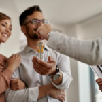 person passing keys to a smiling couple of woman and man