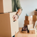 man holds the boxes, other boxes and flower behind on blurred background