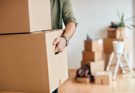 man holds the boxes, other boxes and flower behind on blurred background