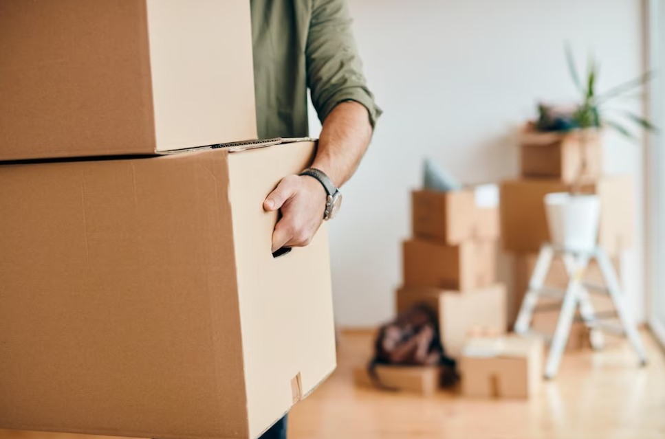 man holds the boxes, other boxes and flower behind on blurred background