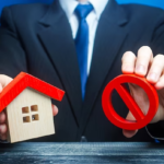 Man holding house and red prohibition symbol no
