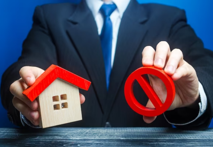 Man holding house and red prohibition symbol no